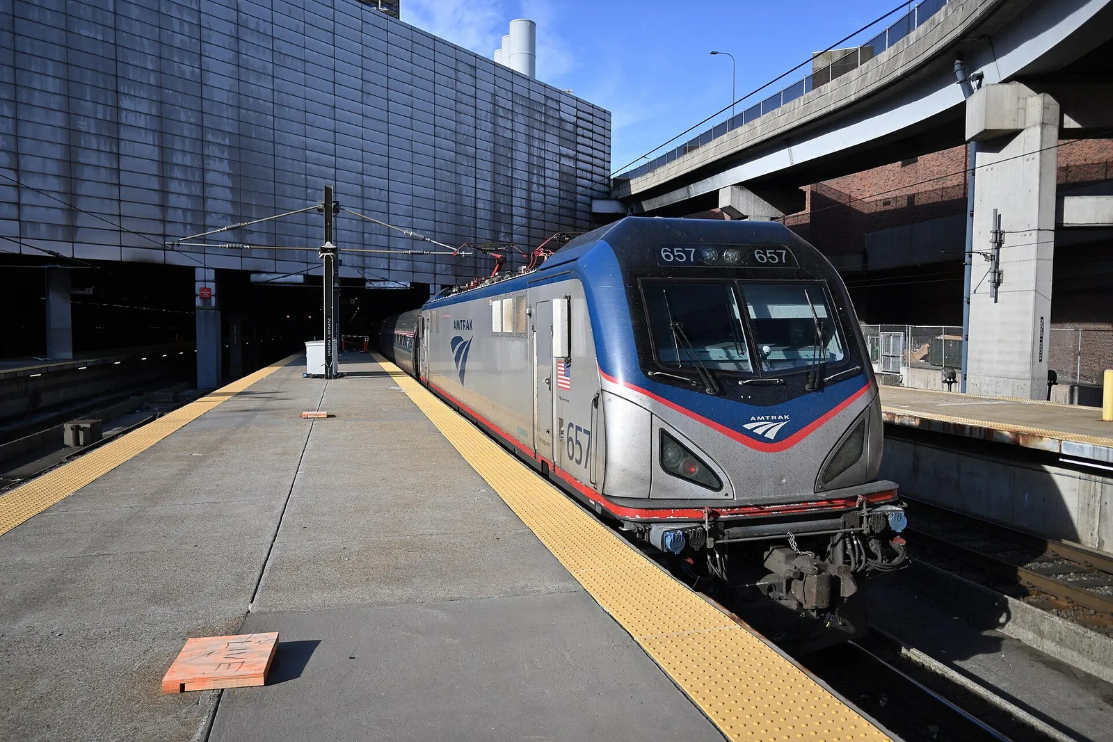 Amtrak passenger train waiting at a station platform with travelers boarding