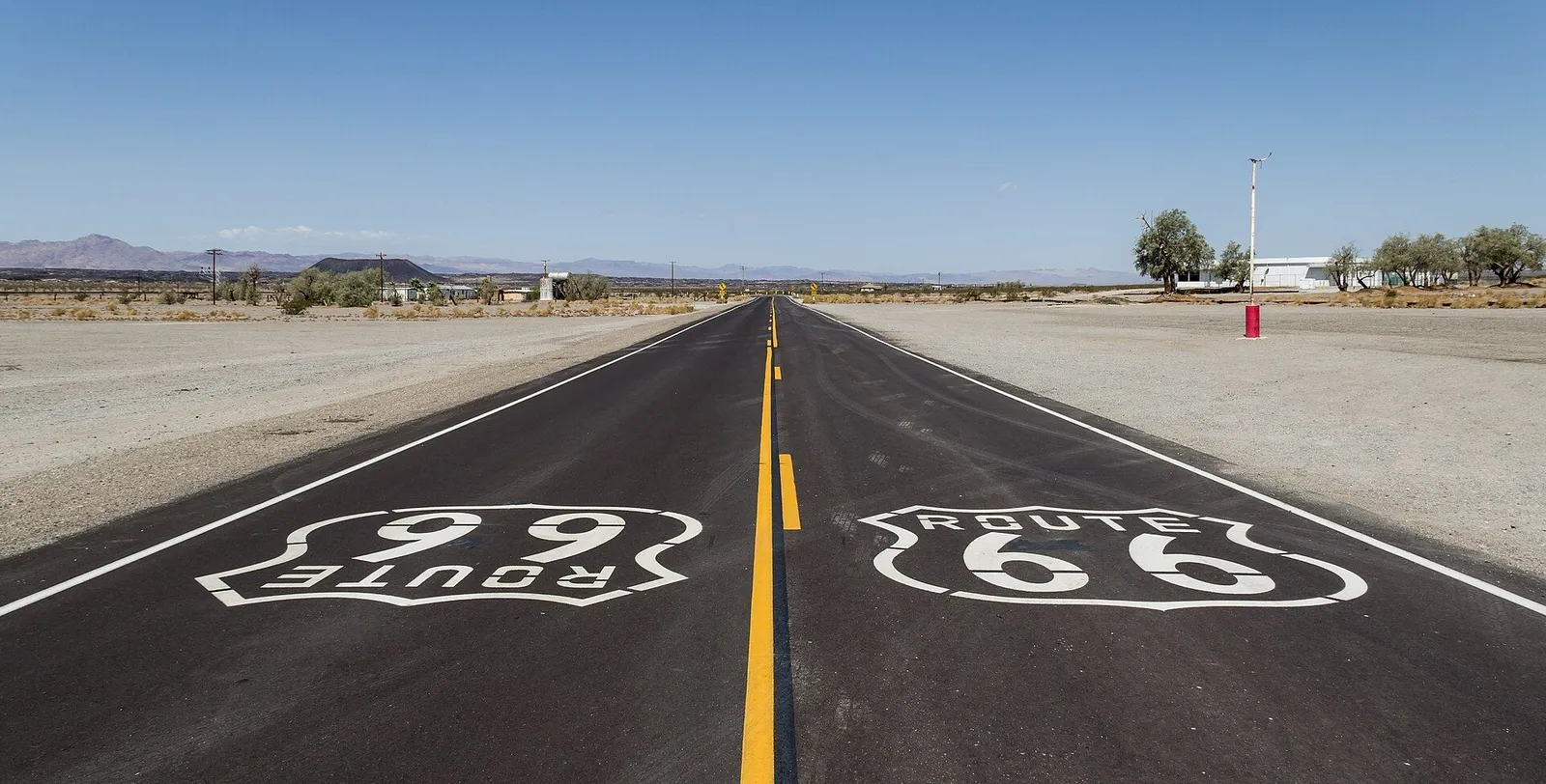 An empty American interstate highway crossing a desert landscape with a road sign
