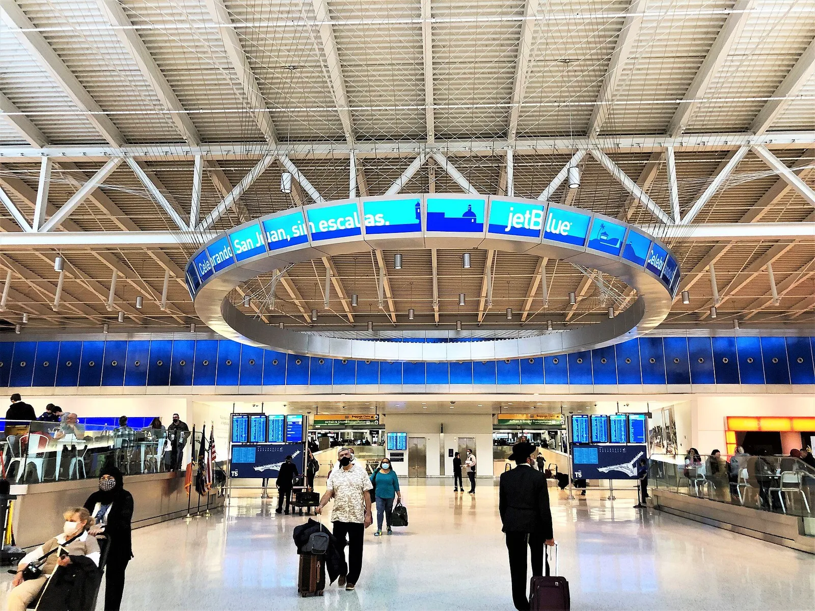 Traveler with a rolling suitcase checking departure boards in a bright American airport terminal