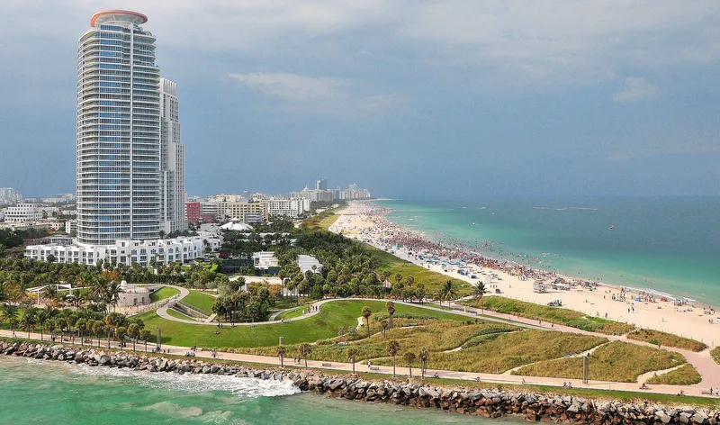 South Beach shoreline with pale sand, turquoise ocean, and palm trees in the foreground