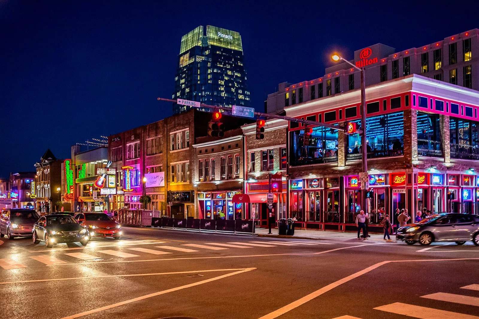 Neon signs of honky-tonk bars glowing on lower Broadway in downtown Nashville at dusk