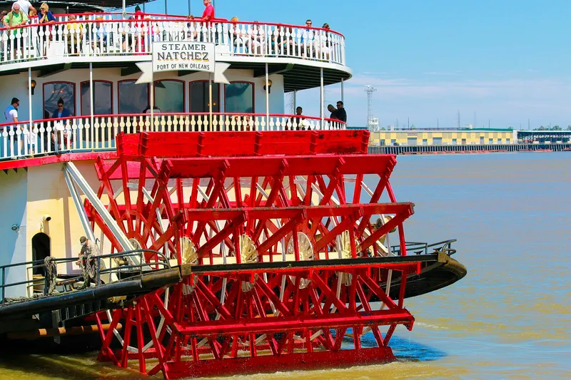 Iron-lace balconies of the French Quarter at dusk with a steamboat on the Mississippi River beyond