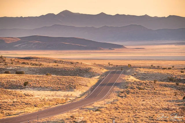 A long straight American highway crossing open desert country under a wide sky