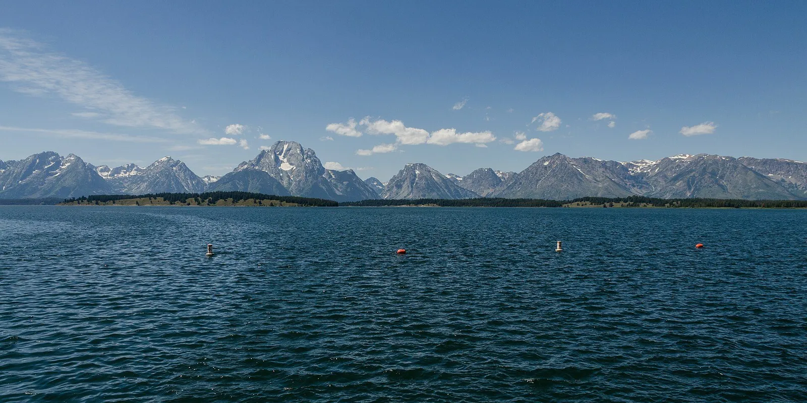 The Grand Teton range reflected in the Snake River at a gravel river landing at dawn
